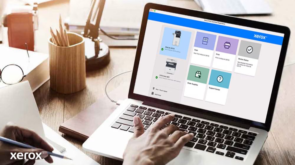 Xerox® Druck- und Scan-Erlebnis: Intuitive Steuerung Die Hände einer Person liegen auf einer Laptoptastatur und auf dem Bildschirm wird die Xerox Print and Scan Experience-Benutzeroberfläche mit Optionen wie „Scannen“, „Drucken“, „Gerätestatus“, „Verbrauchsmaterial bestellen“ und „Support Center“ angezeigt, was auf eine benutzerfreundliche Steuerung hindeutet.
