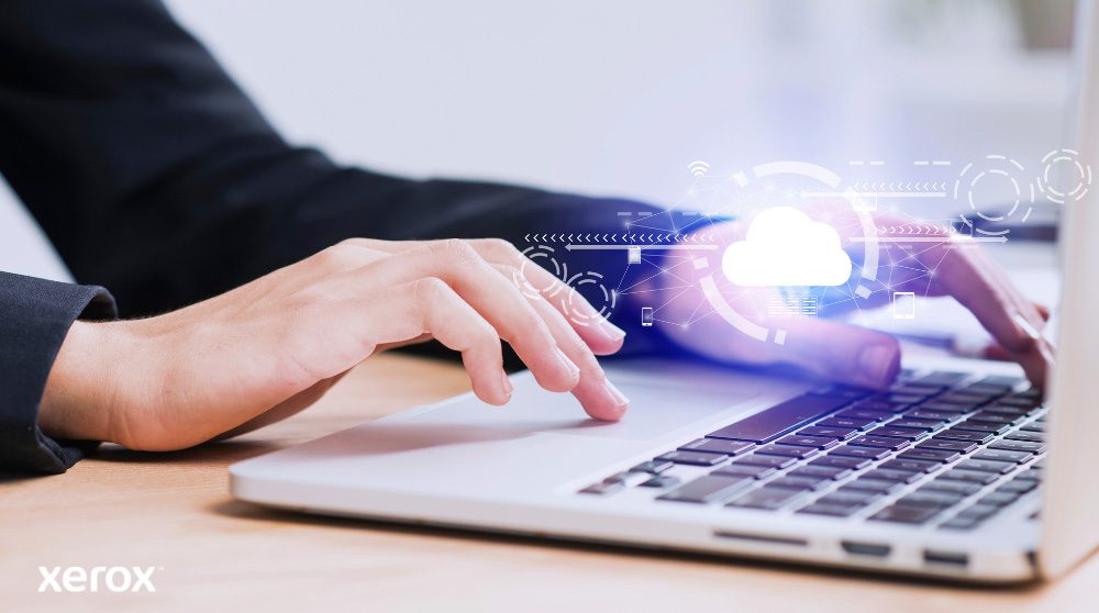 Zu sehen sind die Hände einer Person, die auf einer Laptoptastatur tippt. Über das Bild sind ein leuchtendes Wolkensymbol und Netzwerkverbindungen gelegt, die Cloud-Konnektivität und digitale Arbeitsabläufe symbolisieren.